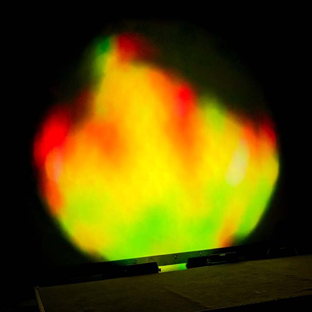 Vari-lite VLHIVE 151 a moving head fixture projecting an array of orange, yellows reds and greens on a wall creating a dappled wash of colour